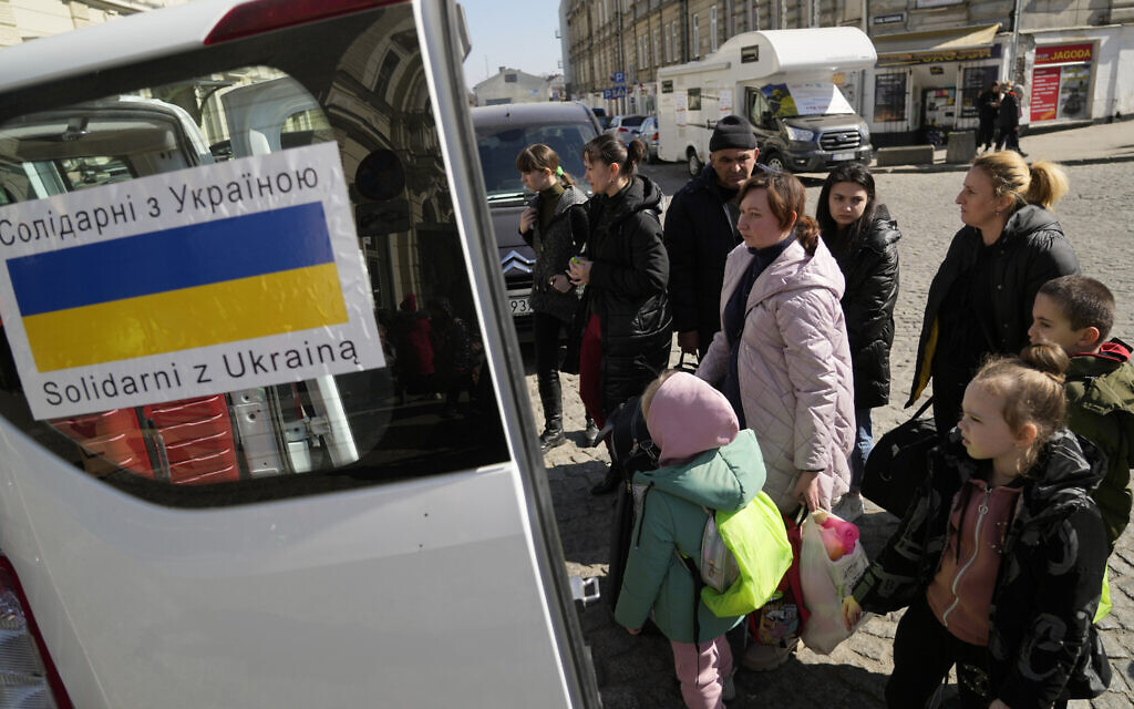 Ukrainian refugees with children board transport at a square next to a railway station in Przemysl, Poland, March 22, 2022. (AP Photo/Sergei Grits)