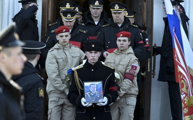 A serviceman carries the photo of Capt. Andrei Paliy, a deputy commander of Russia's Black Sea Fleet, during a farewell ceremony in Sevastopol, Crimea,  March 23, 2022. Paliy was killed in action during fighting with Ukrainian forces in the Sea of Azov port of Mariupol. (AP Photo)
