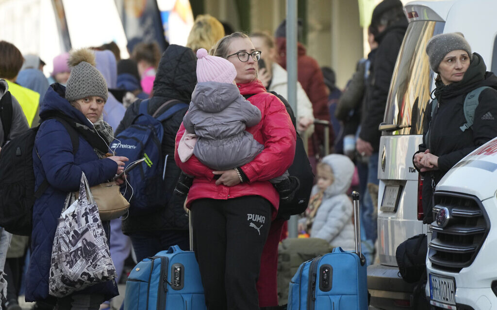Refugees with children wait for a transport after fleeing the war from neighboring Ukraine at a railway station in Przemysl, Poland, on March 24, 2022. (AP Photo/Sergei Grits)