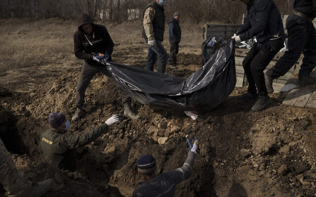 Dead bodies are placed into a mass grave at a cemetery in Kharkiv, Ukraine, on March 26, 2022. (AP Photo/Felipe Dana)