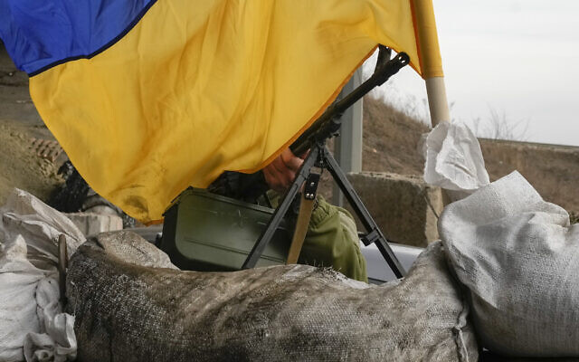 A machine gun emerges from under a Ukrainian national flag on a front line position near Kharkiv, Ukraine, March 26, 2022. (AP Photo/Efrem Lukatsky)