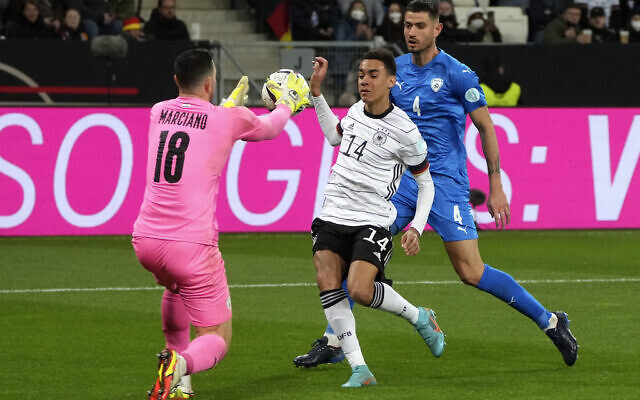 Israel's goalkeeper Ofir Marciano, left, makes a save in front of Germany's Jamal Musiala, center, during the international friendly soccer match between Germany and Israel in Sinsheim, Germany, March 26, 2022. (Michael Probst/AP)