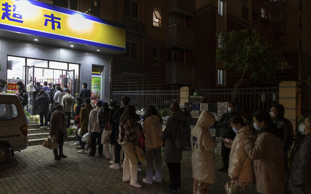 Residents wearing face masks to help protect from the coronavirus line up outside a supermarket at night to buy groceries on Sunday, March 27, 2022, in Shanghai, China. China began locking down most of its largest city of Shanghai on Monday as part of its strict COVID-19 strategy, amid questions over the policy's economic toll on the country. (AP Photo)