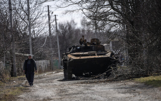 A villager walks next to a destroyed Russian tank near the front line in Brovary, in the outskirts of Kyiv, Ukraine, Monday, March 28, 2022. (AP Photo/Rodrigo Abd)