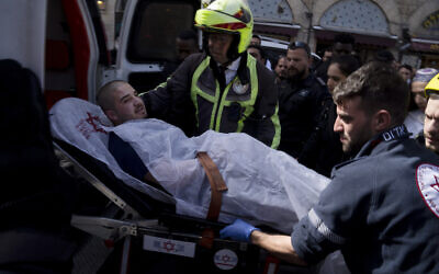 An injured man is loaded into an ambulance after an altercation in the Mahane Yehuda market in Jerusalem during which police shot two men, injuring them, March 30, 2022. (Maya Alleruzzo/AP)