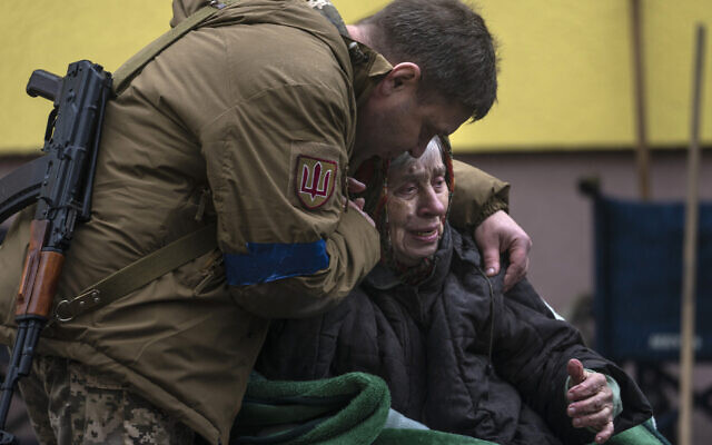 A soldier comforts Larysa Kolesnyk, 82, after being evacuated from Irpin, on the outskirts of Kyiv, Ukraine, March 30, 2022. (AP Photo/Rodrigo Abd)