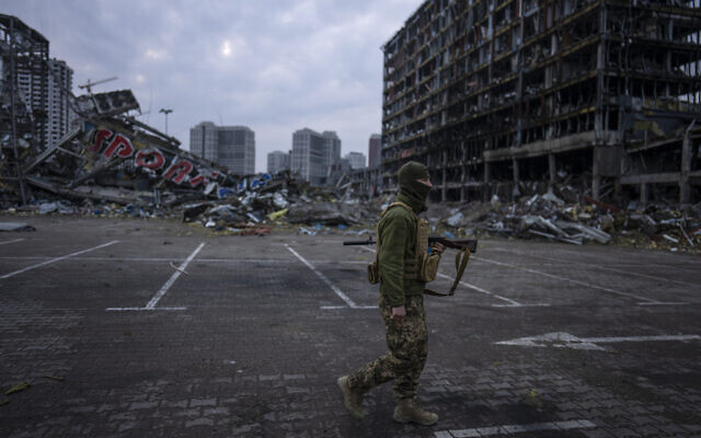 A soldier walks amid the destruction caused after the shelling of a shopping center in Kyiv, Ukraine, on March 30, 2022. (AP Photo/Rodrigo Abd)