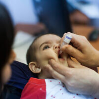 A child is given an oral vaccine for polio in Neve Yaakov, Jerusalem, on September 10 2013. (Yonatan Sindel/Flash90)