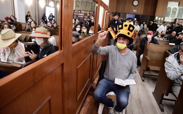 People read from Megillat Esther (the Story of Esther) during the Jewish holiday of Purim, at the Great Synagogue in Tel Aviv, on March 16, 2022. (Avshalom Sassoni/Flash90)