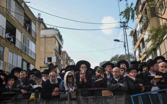 Ultra-Orthodox Jewish men pray and wait as they gather outside the home of Rabbi Chaim Kanievsky in Bnei Brak, ahead of his funeral on March 20, 2022. (Yonatan Sindel/ Flash90)