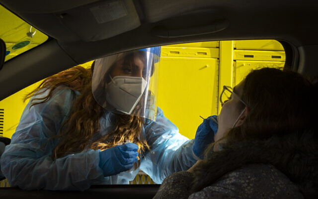 A Magen David worker takes a swab sample at a COVID-19 drive-thru testing site in Jerusalem, on March 22, 2022. (Olivier Fitoussi/Flash90)