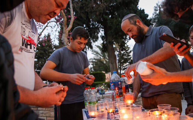 Jewish men light candles after the funeral of police officer Amir Khoury during his funeral in Nof Hagalil, Israel, March 31, 2022. (Photo by David Cohen/Flash90)