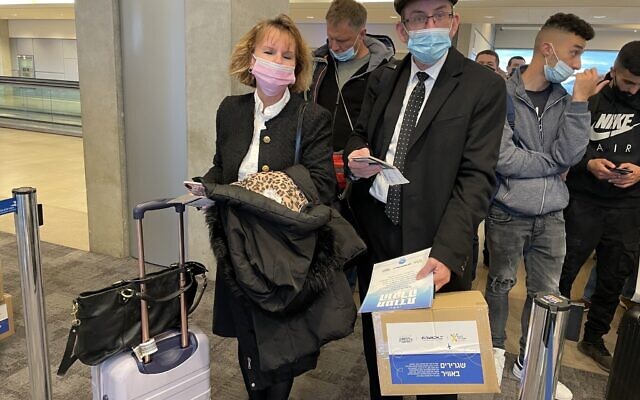 El Al passengers boarding a plane to Bucharest with packages for Ukrainian refugees at Ben Gurion Airport on March 14, 2022. (Sue Surkes/Times of Israel)
