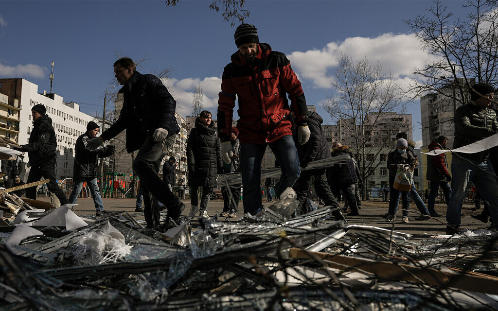 People clear debris outside a medical center damaged after parts of a Russian missile, shot down by Ukrainian air defense, landed on a nearby apartment block, according to authorities, in Kyiv, Ukraine, March 17, 2022. (AP Photo/Vadim Ghirda)