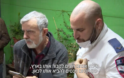 The father of Roman Brodsky, an Israeli killed in Ukraine, at left, discusses his burial arrangements during a phone call with his son's partner in Ukraine. A Magen David Adom paramedic, right, helped facilitate the call. (Screenshot/Channel 12)