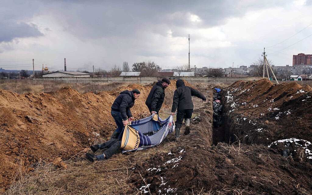 Dead bodies are put into a mass grave on the outskirts of Mariupol, Ukraine, March 9, 2022, as people cannot bury their loved ones because of the heavy shelling by Russian forces. (AP Photo/Evgeniy Maloletka)