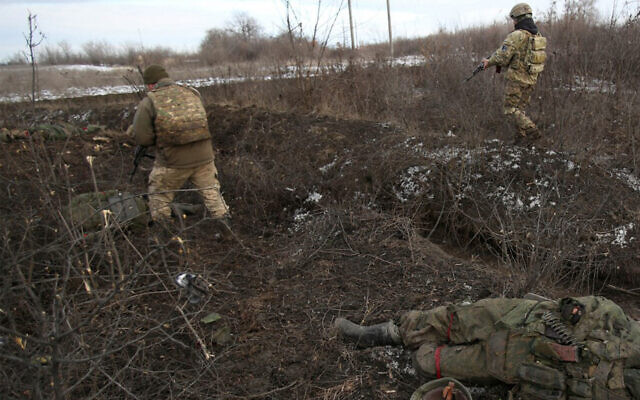 Ukrainian troops walk past a body, following fighting against Russian forces and Russia-backed separatists near the village of Zolote, Lugansk region, March 6, 2022. (Anatolii Stepanov/AFP)