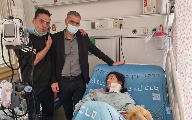 Manwar Burqan, 11, recovers at Hadassah Hospital after being struck by a police sound grenade, alongside her father (far left) and left-wing Meretz MK Mossi Raz (center) on March 1, 2021 (Credit: Noa Pinto)