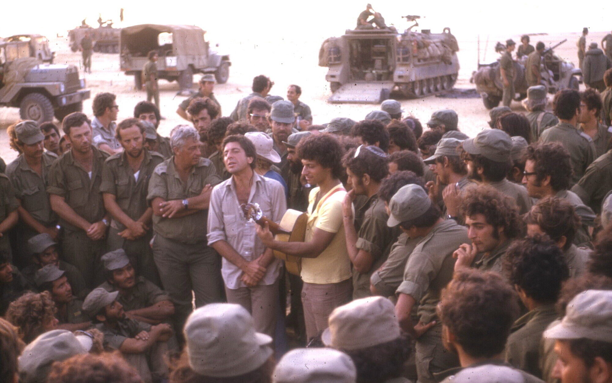 Leonard Cohen, center, performs with Israeli singer Matti Caspi, on guitar, for Israeli troops in the Sinai in 1973. Ariel Sharon is to the left of Cohen, with arms crossed (Yaakovi Doron)