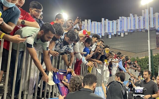 Fans strain for autographs from some of the soccer legends that played at a festive soccer match between an Abraham Accords team made up of players from Israel, the UAE, Bahrain and Morocco and one comprising world soccer stars, Dubai, March 29, 2022. (Sue Surkes/Times of Israel)