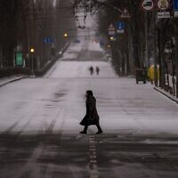People walk along an empty road during curfew, in Kyiv, Ukraine, on Tuesday, March 1, 2022. (AP Photo/Emilio Morenatti)