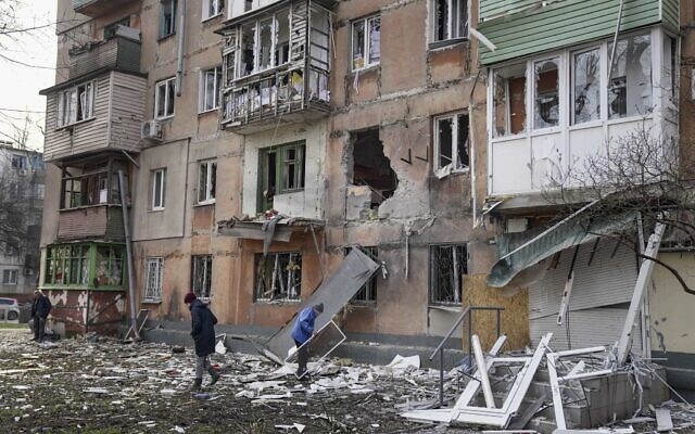 People walk next to an apartment building hit by shelling in Mariupol, Ukraine, on March 7, 2022. (AP Photo/Evgeniy Maloletka)