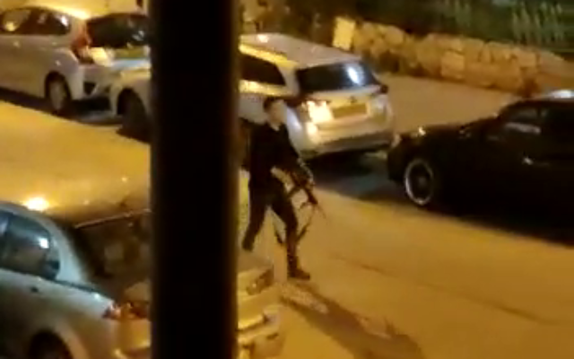 A terrorist aims a rifle at a passerby in Bnei Brak, on March 29, 2022. (Screen capture)