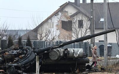A local resident walks past a destroyed Russian tank in Dmytrivka, west of Kyiv, undated (Genya SAVILOV / AFP)
