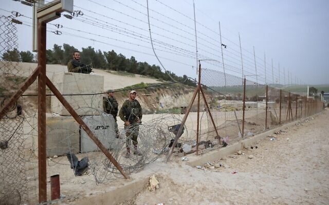 Israeli soldiers stand guard at a breach in the security fence which have been used daily by thousands of Palestinian workers to illegally enter Israel for work, near the Meitar checkpoint, south of Hebron in the West Bank, on April 3, 2022. (Hazem Bader/AFP)