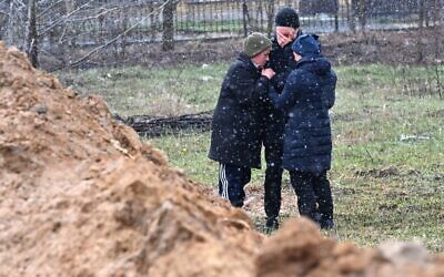 People react as they gather close to a mass grave in the town of Bucha, just northwest of the Ukrainian capital Kyiv on April 3, 2022. (Sergei SUPINSKY / AFP)