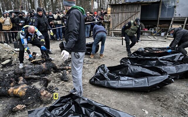 Policemen and city workers carry six partially burnt bodies into body bags as reporters attend in the town of Bucha on April 5, 2022, as Ukrainian officials say over 400 civilian bodies have been recovered from the wider Kyiv region, many of which were buried in mass graves (Genya SAVILOV / AFP)