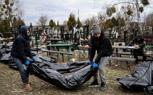 Workers line up bodies for identification by forensic personnel and police officers in the cemetery in Bucha, north of Kyiv, on April 6, 2022, after hundreds of civilians were found dead in areas from which Russian troops have withdrawn around Ukraine's capital, including the town of Bucha. (Ronaldo Schemidt/AFP)