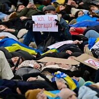 A man holds up a placard which reads "I am Mariupol!!" as pro-Ukrainian activists stage a "Die-in" during a protest under the slogan "Stop promising, start acting!" to call for an immediate embargo on oil, gas and coal imports from Russia in front of the Bundestag (lower house of parliament) in Berlin, April 6, 2022. (John MACDOUGALL / AFP)