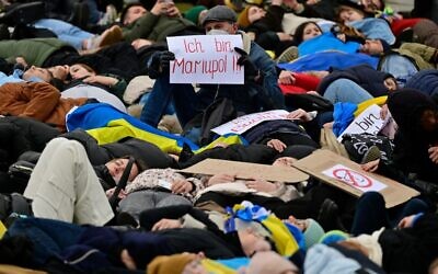A man holds up a placard which reads "I am Mariupol!!" as pro-Ukrainian activists stage a "Die-in" during a protest under the slogan "Stop promising, start acting!" to call for an immediate embargo on oil, gas and coal imports from Russia in front of the Bundestag (lower house of parliament) in Berlin, April 6, 2022. (John MACDOUGALL / AFP)