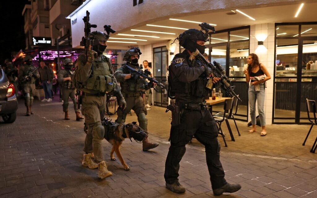 Security forces walk outside a restaurant following a deadly terror attack on Dizengoff Street in Tel Aviv on April 7, 2022. (Ahmad Gharabli/AFP)
