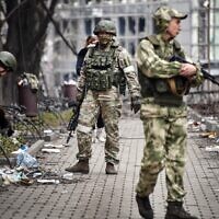 Russian soldiers walk along a street in Mariupol on April 12, 2022. (Alexander Nemenov/AFP)