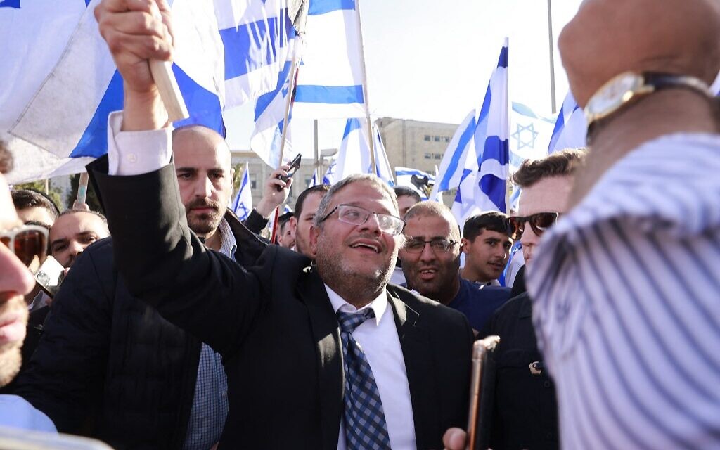 MK Itamar Ben Gvir, leader of the far-right Otzma Yehudit (Jewish Power) faction of the Religious Zionist party, raises an Israeli flag in Safra Square in Jerusalem on April 20, 2022, at the start of a planned nationalist march. (Menahem Kahana / AFP)