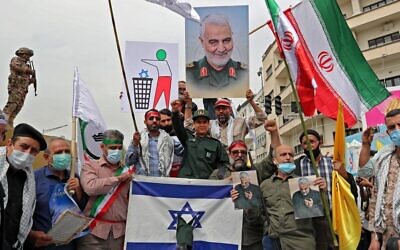 Iranians prepare to set an Israeli flag on fire next to a picture of late Iranian general Qasem Soleimnai during a rally marking al-Quds (Jerusalem) day in Tehran, on April 29, 2022. (AFP)