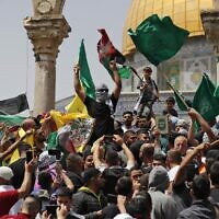 Palestinians wave Palestinian and Islamic flags as they rally at the Al-Aqsa Mosque on the Temple Mount in Jerusalem, following the last Friday prayers of the Muslim holy month of Ramadan, on April 29, 2022. (Ahmad Gharabli/AFP)