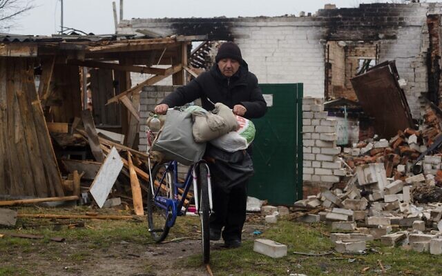 Mykola, a local resident, takes valuable items from his destroyed house by bicycle on April 9, 2022 in Novoselivka, Chernihiv suburbs, Ukraine. (Anastasia Vlasova/Getty Images via AFP)