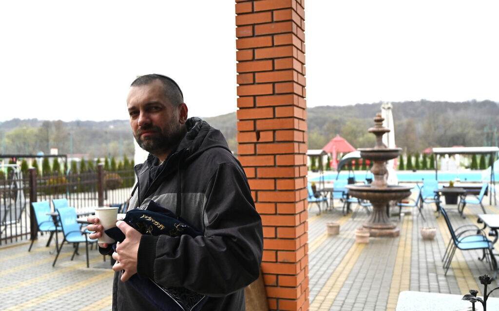 Akivah Artamonov clasps his prayer kit while having coffee at the Jewish refugee camp in Irshava, Ukraine, April 5, 2022. (Cnaan Liphshiz/ JTA)