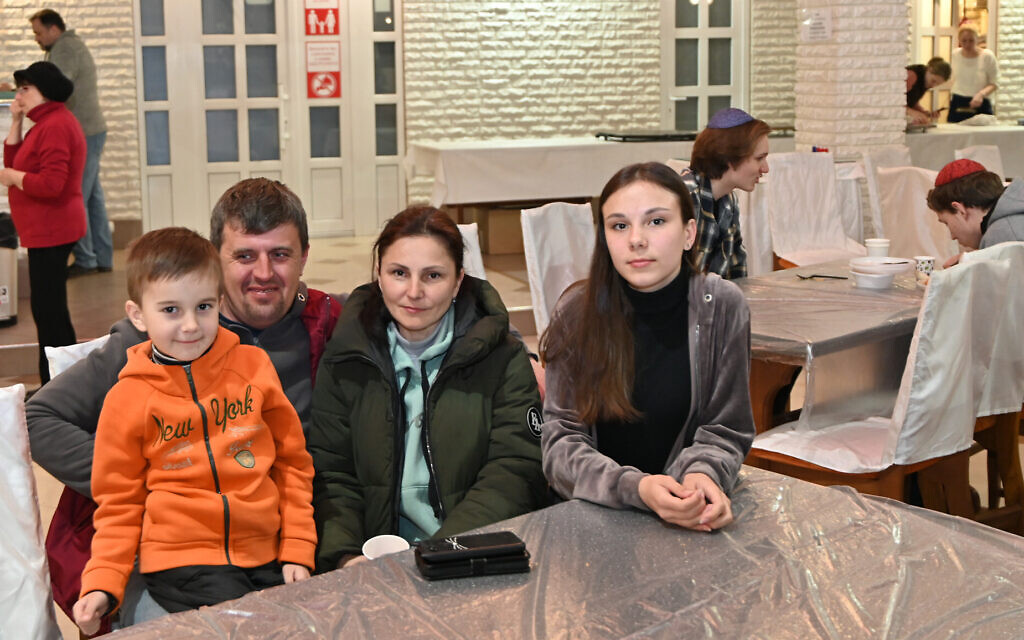 Yevgeni and Anya Rozvadoskyy sit between their children, Vadim and Dasha, at the Jewish refugee camp in Irshava, Ukraine, April 4, 2022. (Cnaan Liphshiz/ JTA)