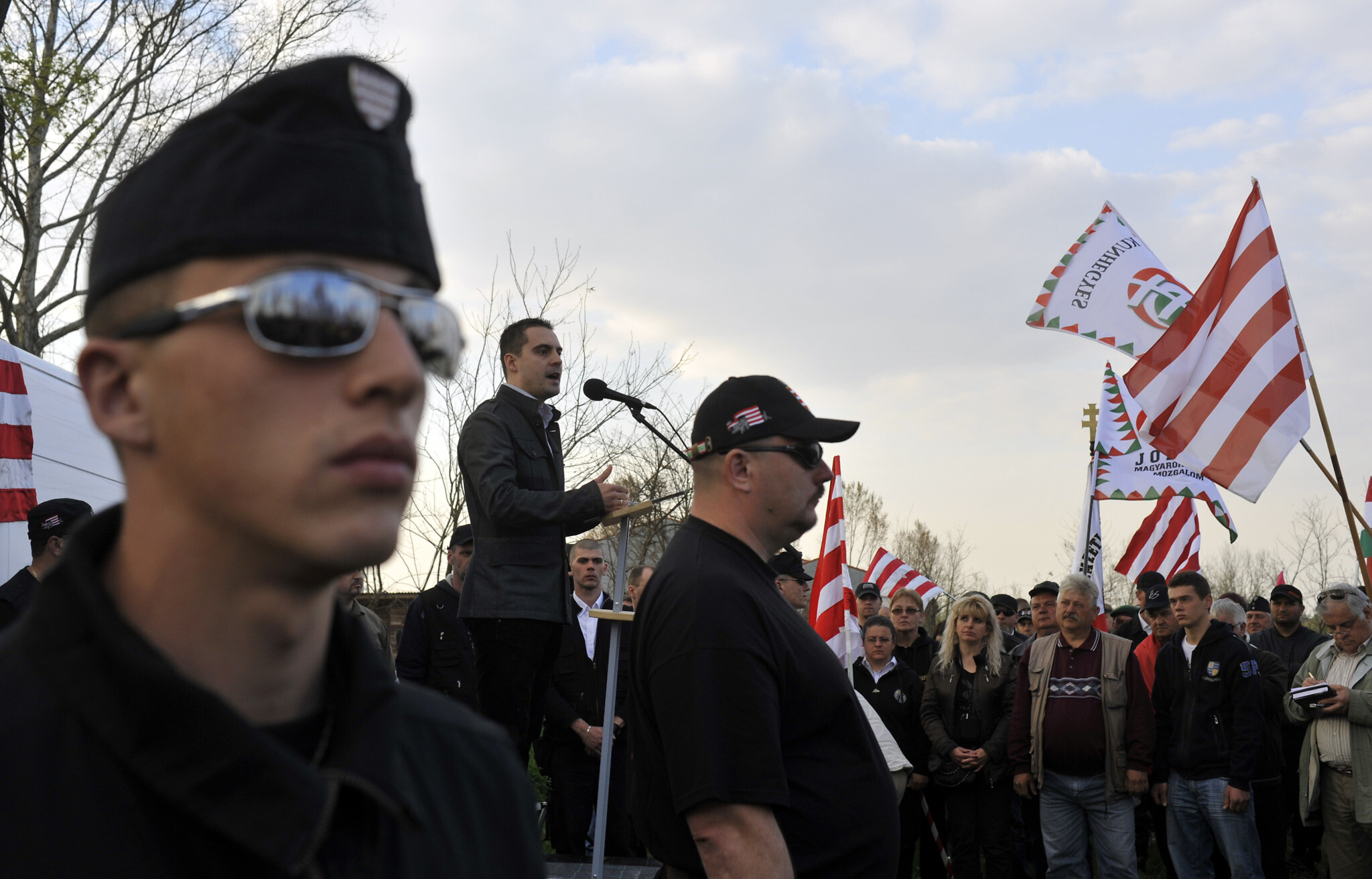 Members of a controversial extreme-right vigilante group stand guard while Gabor Vona, then-leader of the extreme-right Jobbik party, talks during a demonstration in the town of Hajduhadhaz, eastern Hungary, April 17, 2011. Vigilante groups and paramilitary organizations entered the town two weeks prior, conducting foot and car patrols to spread fear in the local Gypsy population. (AP Photo/Bela Szandelszky)