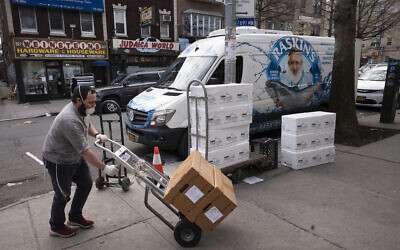 An employee of Raskin's Fish Market, which specializes in kosher food, moves boxes of fish into the store in the Crown Heights neighborhood of Brooklyn, on Tuesday, April 7, 2020, during the coronavirus pandemic in New York. (AP Photo/Mark Lennihan)