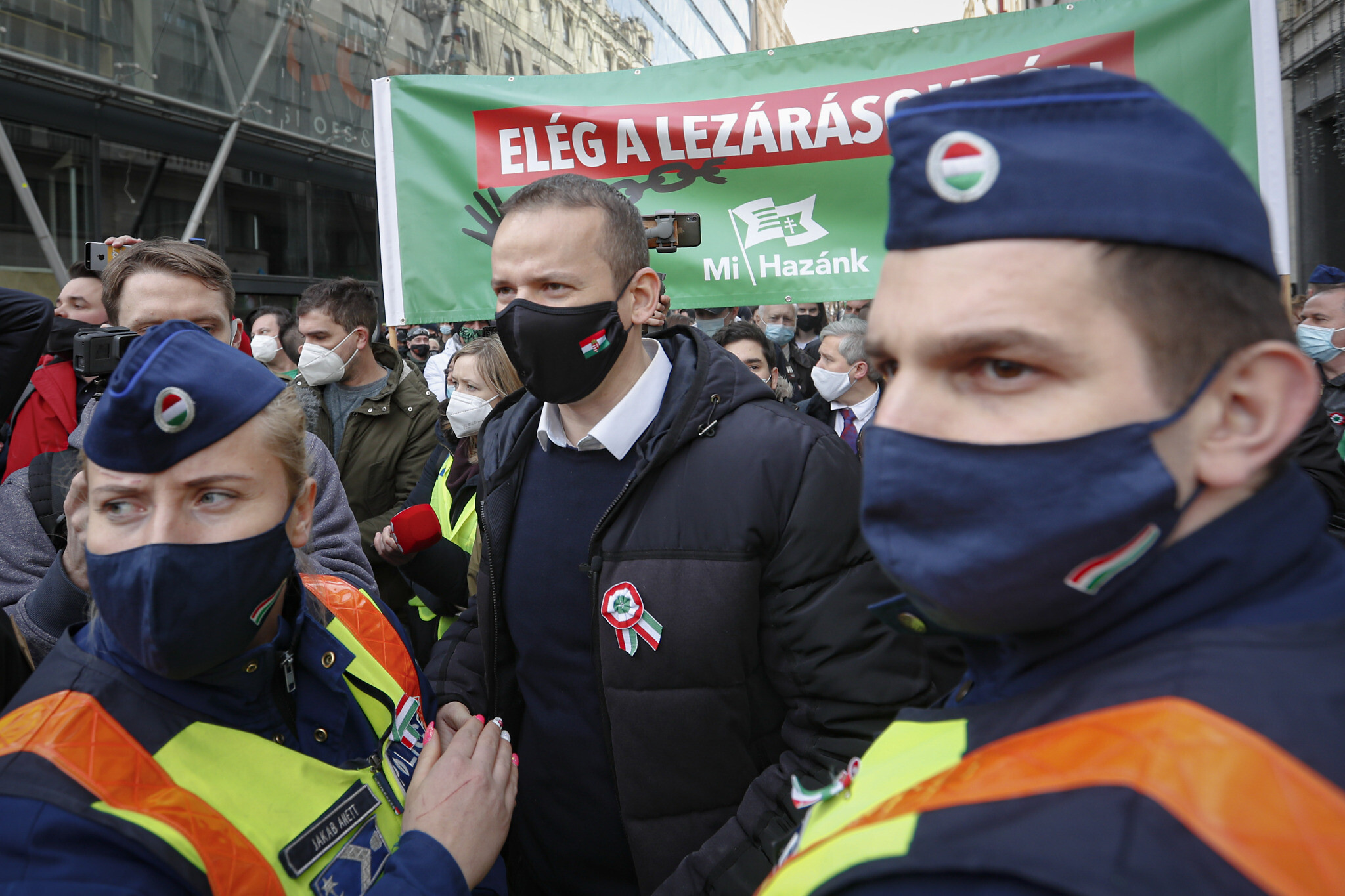 Laszlo Toroczkai, center, head of the Our Homeland Movement, is flanked by police officers during a protest in Budapest, Hungary, Monday, March 15, 2021. (AP Photo/Laszlo Balogh)