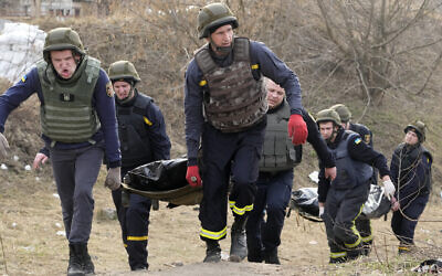 Ukrainian emergency services carry bodies of civilians killed by the Russian troops over the destroyed bridge in Irpin close to Kyiv, Ukraine, March 31, 2022. (AP Photo/Efrem Lukatsky)