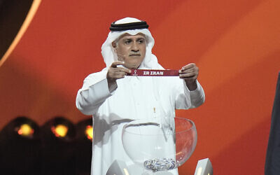 Former Qatari soccer international Adel Ahmed MalAllah holds up the name of Iran during the 2022 soccer World Cup draw at the Doha Exhibition and Convention Center in Doha, Qatar, Friday, April 1, 2022. (AP Photo/Hassan Ammar)