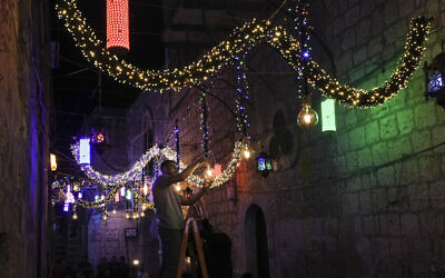 A Palestinian man hangs decorative lights in preparation for the holy Muslim month of Ramadan, at the streets of Jerusalem's Old City, April 1, 2022. (AP Photo/Mahmoud Illean)