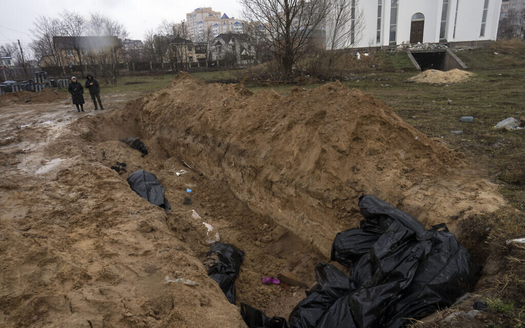 Neighbours gather next to a mass grave in Bucha, in the outskirts of Kyiv, Ukraine, April 3, 2022. (AP Photo/Rodrigo Abd)