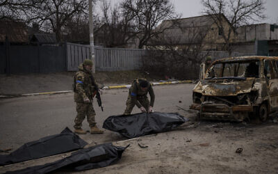 Ukrainian soldiers recover the remains of four killed civilians from inside a charred vehicle in Bucha, outskirts of Kyiv, Ukraine, on April 5, 2022. (AP Photo/Felipe Dana)